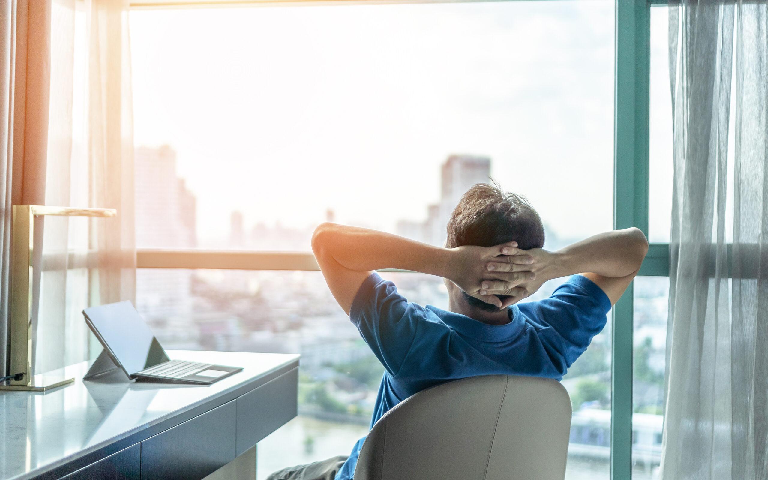 Life-work balance and city living lifestyle concept of business Life-work balance and city living lifestyle concept of business man relaxing, take it easy in office or hotel room resting with thoughtful mind thinking of life quality looking forward to cityscape